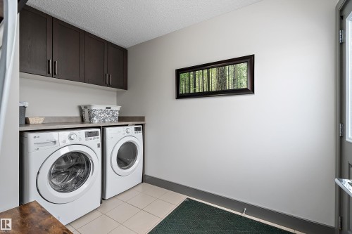 The laundry area features a washer and dryer, dark wood cabinetry, and a countertop space - 7776 Eifert Crescent Nw, Edmonton, AB - Indoor Photo Showing Laundry Room