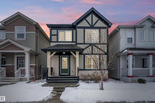 The property presents an appealing facade with a dark-trimmed gable roof and an inviting covered porch - 7776 Eifert Crescent Nw, Edmonton, AB - Outdoor With Facade