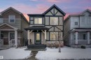 The property presents an appealing facade with a dark-trimmed gable roof and an inviting covered porch - 7776 Eifert Crescent Nw, Edmonton, AB  - Outdoor With Facade 