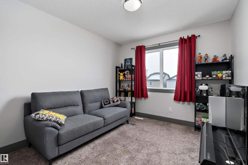 This room features light-colored walls and a window with red curtains - 7776 Eifert Crescent Nw, Edmonton, AB - Indoor