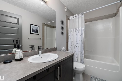 Bathroom featuring a dark wood vanity with a light-colored countertop and a white oval sink - 7776 Eifert Crescent Nw, Edmonton, AB - Indoor Photo Showing Bathroom
