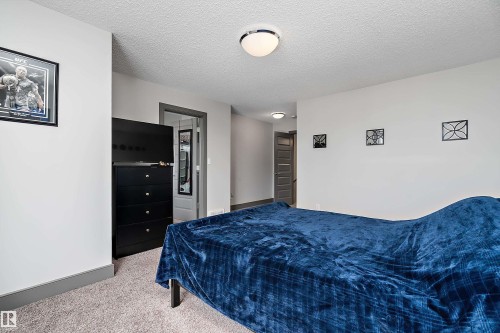 This room features light-colored walls, a textured ceiling, and gray baseboards - 7776 Eifert Crescent Nw, Edmonton, AB - Indoor Photo Showing Bedroom