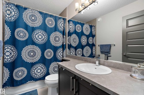 Bathroom featuring a vanity with an integrated sink, a large mirror, and an overhead light fixture - 7776 Eifert Crescent Nw, Edmonton, AB - Indoor Photo Showing Bathroom
