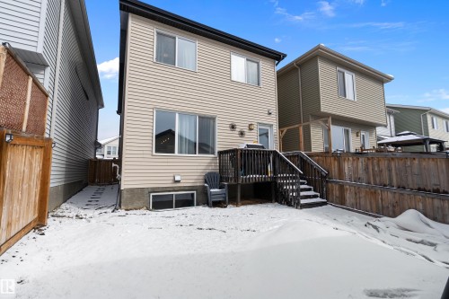 The property features a two-story exterior with light-colored siding, a dark roof, and a ground-level deck with stairs leading to the yard - 7776 Eifert Crescent Nw, Edmonton, AB - Outdoor With Exterior