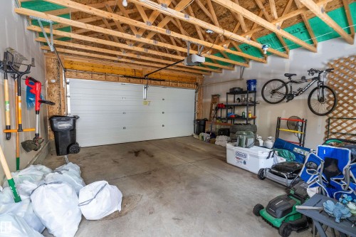 The garage features exposed wooden beams, a concrete floor, and a white garage door - 7776 Eifert Crescent Nw, Edmonton, AB - Indoor Photo Showing Garage