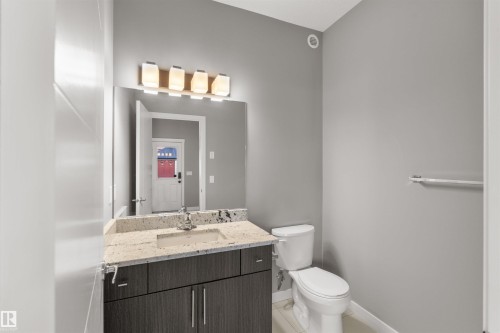 The bathroom features a vanity with a light-colored countertop and a rectangular sink, complemented by a large mirror and modern lighting fixture - 4016 Allan Crescent, Edmonton, AB - Indoor Photo Showing Bathroom