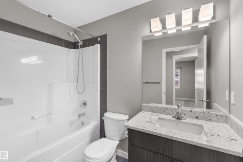 The bathroom features a white bathtub with a shower, a modern vanity with a granite countertop, and a large mirror - 4016 Allan Crescent, Edmonton, AB - Indoor Photo Showing Bathroom