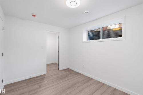 This room features light-toned wood-style flooring, a window, and white walls - 4016 Allan Crescent, Edmonton, AB - Indoor Photo Showing Other Room