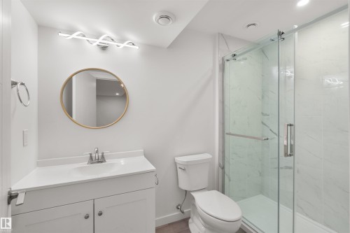 Bathroom featuring a modern vanity with an integrated sink, a circular mirror, and a glass-enclosed shower with tiled walls - 4016 Allan Crescent, Edmonton, AB - Indoor Photo Showing Bathroom