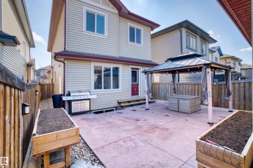The property features a backyard with a large concrete patio, a gazebo with privacy curtains, and raised wooden garden beds - 4016 Allan Crescent, Edmonton, AB - Outdoor With Deck Patio Veranda With Exterior