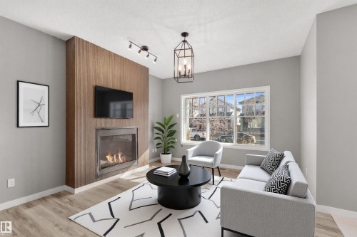 The living area features a fireplace with a wood-paneled surround, light-colored flooring, and a large window providing views of the neighborhood - 4016 Allan Crescent, Edmonton, AB - Indoor Photo Showing Living Room With Fireplace