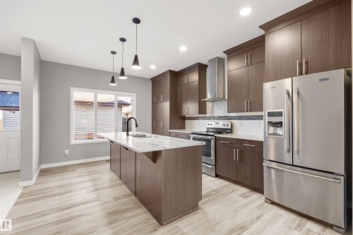 The kitchen features an island with a light-colored countertop, dark cabinetry, and stainless steel appliances - 4016 Allan Crescent, Edmonton, AB - Indoor Photo Showing Kitchen With Stainless Steel Kitchen With Upgraded Kitchen