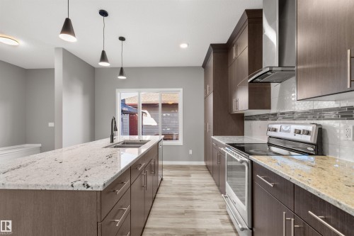 The kitchen features an expansive island with a double basin sink and a light-toned granite countertop - 4016 Allan Crescent, Edmonton, AB - Indoor Photo Showing Kitchen With Double Sink With Upgraded Kitchen