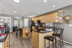 The kitchen features light wood cabinetry, dark granite countertops, and a tile backsplash - 