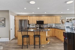 The kitchen features light wood cabinetry, a central island with a dark countertop, and matching dark countertops along the perimeter - 
