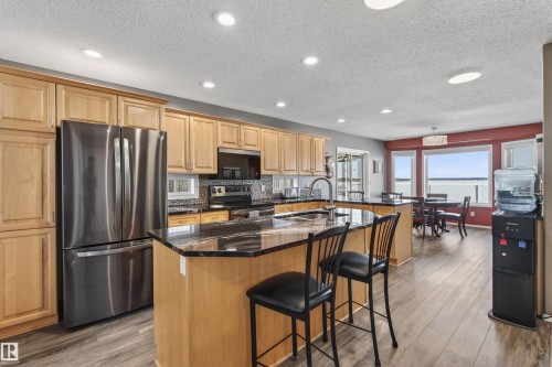 The kitchen features wood cabinetry, a stainless steel refrigerator, and a kitchen island with a dark countertop - #12 61212  Rr 463, Rural Bonnyville M.D., AB - Indoor Photo Showing Kitchen