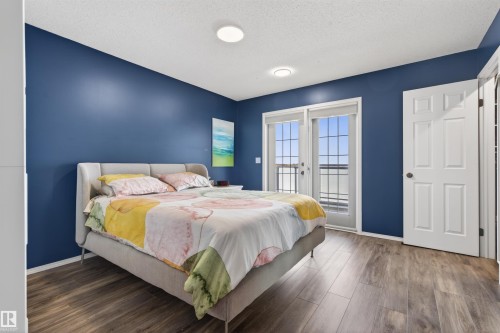 This room features dark hardwood style flooring and a door providing exterior access - #12 61212  Rr 463, Rural Bonnyville M.D., AB - Indoor Photo Showing Bedroom