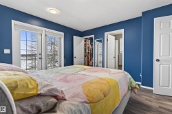 This bedroom features a view of the outdoors through a pair of double glass doors, a closet with bifold doors, and wood-style flooring - 