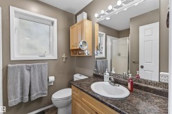 Bathroom with a window, vanity with a countertop and sink, and a shower with a clear glass door - 