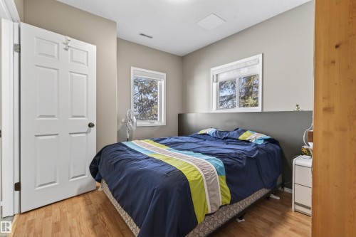 This room features hardwood flooring, two windows providing natural light, and a white paneled door - #12 61212  Rr 463, Rural Bonnyville M.D., AB - Indoor Photo Showing Bedroom
