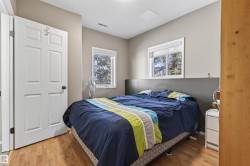 This room features hardwood flooring, two windows providing natural light, and a white paneled door - 