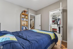 This room features light gray walls, wood flooring, and a closet with custom built-in shelving and drawers - 
