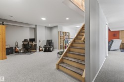 The property features an interior staircase with wood treads and a wood railing, recessed lighting, and light grey carpeting throughout - 