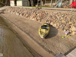 Waterfront property featuring a sandy beach, a natural stone retaining wall, and a wooden dock - 