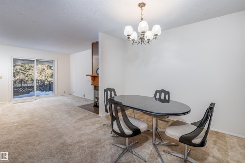 This inviting living area features soft carpeting, a fireplace with a wooden mantel, and a sliding glass door providing external views - 108 Forest Grove, St. Albert, AB - Indoor Photo Showing Dining Room