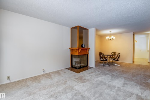 Living area featuring light-colored carpet flooring and a fireplace with a wood mantle - 108 Forest Grove, St. Albert, AB - Indoor With Fireplace