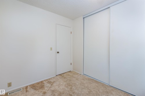 This room features neutral-toned carpet, white walls, and a door with a round knob - 108 Forest Grove, St. Albert, AB - Indoor Photo Showing Other Room