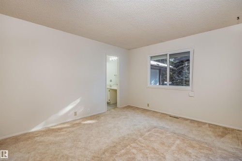 This spacious room features neutral-toned carpet, light-colored walls, and a window providing views of exterior trees - 108 Forest Grove, St. Albert, AB - Indoor Photo Showing Other Room