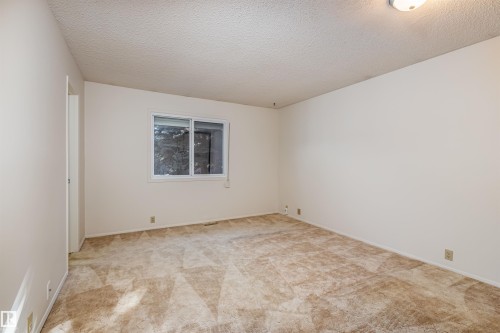 This room features neutral-toned carpeting, a window providing natural light, and a white ceiling with an overhead light fixture - 108 Forest Grove, St. Albert, AB - Indoor Photo Showing Other Room