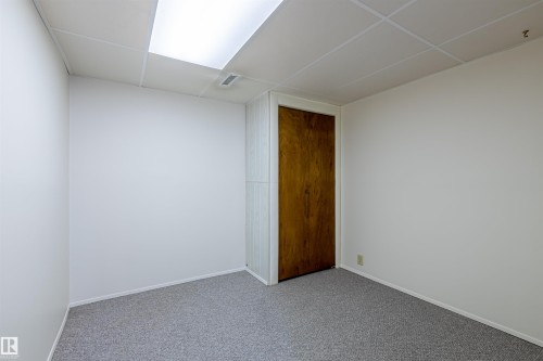 Room featuring light-colored walls, gray carpet, a wooden door, and a drop ceiling with integrated lighting - 108 Forest Grove, St. Albert, AB - Indoor Photo Showing Other Room