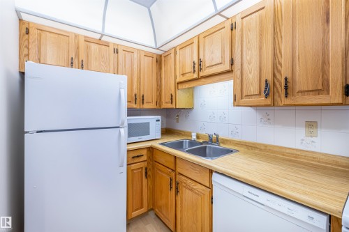 The kitchen features wooden cabinetry, white appliances, and a double basin sink - 108 Forest Grove, St. Albert, AB - Indoor Photo Showing Kitchen With Double Sink