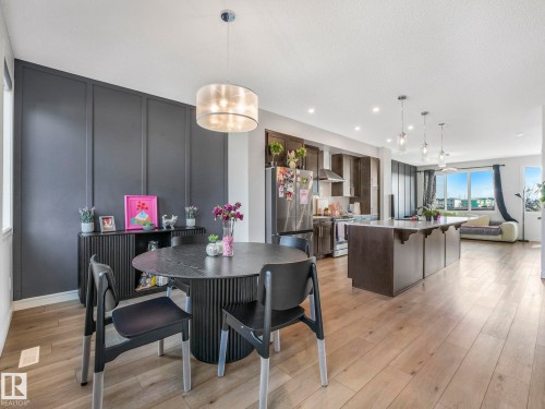 This property features an open-concept living space with light-toned flooring, a kitchen island, and a dining area with a modern chandelier - 2636 192 Street, Edmonton, AB - Indoor Photo Showing Dining Room
