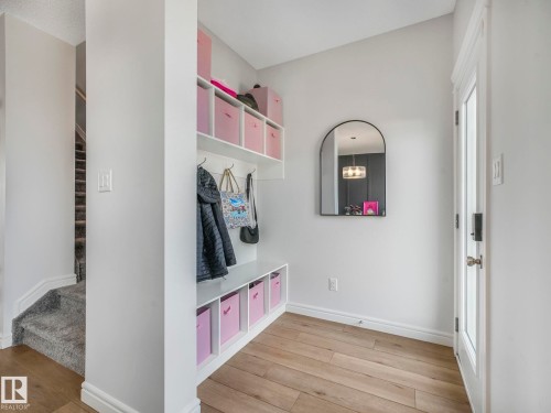 Entryway featuring light hardwood flooring, a built-in storage unit with shelving, and a mirrored wall accent - 2636 192 Street, Edmonton, AB - Indoor Photo Showing Other Room