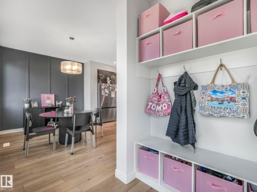 This property features light wood flooring, a dining area with a circular table and dark chairs, and a contemporary light fixture - 2636 192 Street, Edmonton, AB - Indoor