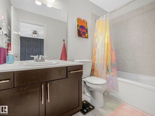 Bathroom featuring a vanity with a white countertop and dark wood cabinetry, a built-in bathtub, and tiled walls in the shower area - 2636 192 Street, Edmonton, AB - Indoor Photo Showing Bathroom