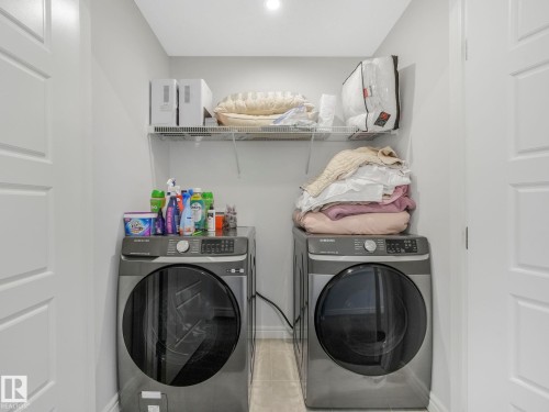 This dedicated laundry area features a washing machine and a dryer, along with a wire shelf for storage - 2636 192 Street, Edmonton, AB - Indoor Photo Showing Laundry Room