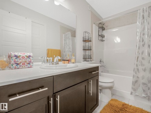 Bathroom featuring a white vanity with dark cabinetry and a built-in sink, a large mirror, and a bathtub with a shower - 2636 192 Street, Edmonton, AB - Indoor Photo Showing Bathroom