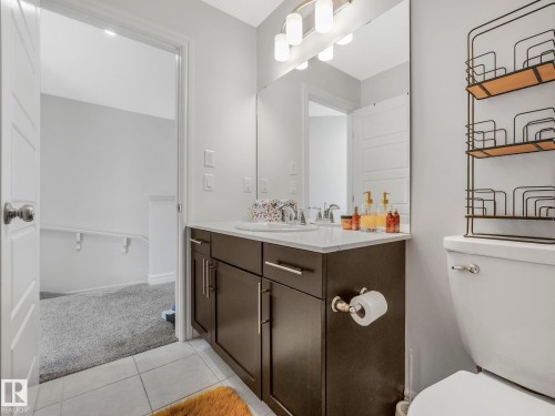 The bathroom features a dual sink vanity with a white countertop and dark wood cabinetry, a large mirror, and tiled flooring - 2636 192 Street, Edmonton, AB - Indoor Photo Showing Bathroom