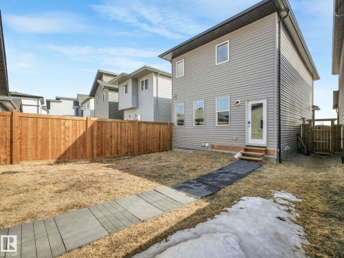 The property features a fenced yard with a wooden fence and a pathway leading to a rear entrance - 2636 192 Street, Edmonton, AB - Outdoor