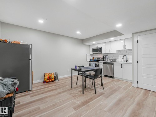 Well-lit open concept kitchen and dining area featuring light wood-look flooring, white cabinetry, and stainless steel appliances - 2636 192 Street, Edmonton, AB - Indoor