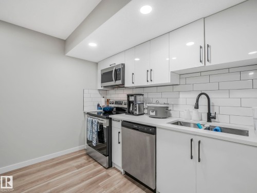 The kitchen features white cabinetry with dark hardware, stainless steel appliances, a subway tile backsplash, and light-toned flooring - 2636 192 Street, Edmonton, AB - Indoor Photo Showing Kitchen With Double Sink