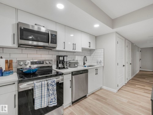 The kitchen features white cabinetry, stainless steel appliances, a white subway tile backsplash, and light-toned flooring - 2636 192 Street, Edmonton, AB - Indoor Photo Showing Kitchen