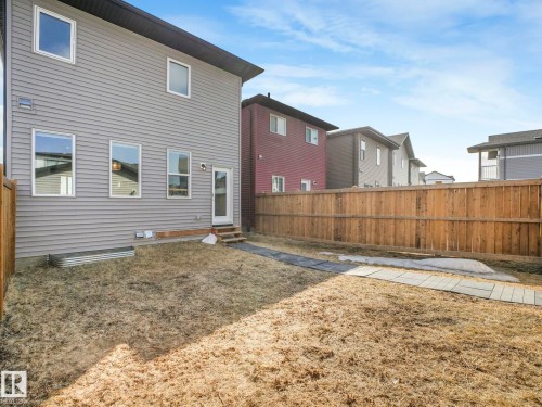 The property features a fenced yard with a stone pathway, a door providing exterior access, and a metal planter box - 2636 192 Street, Edmonton, AB - Outdoor With Exterior