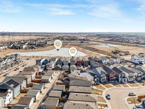 Aerial view of a residential neighbourhood featuring detached houses with varying exterior colors and roof styles, and a body of water in the background - 2636 192 Street, Edmonton, AB - Outdoor With View