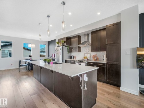 The kitchen features dark cabinetry, a white countertop, and stainless steel appliances including a range with an overhead hood - 2636 192 Street, Edmonton, AB - Indoor Photo Showing Kitchen With Upgraded Kitchen