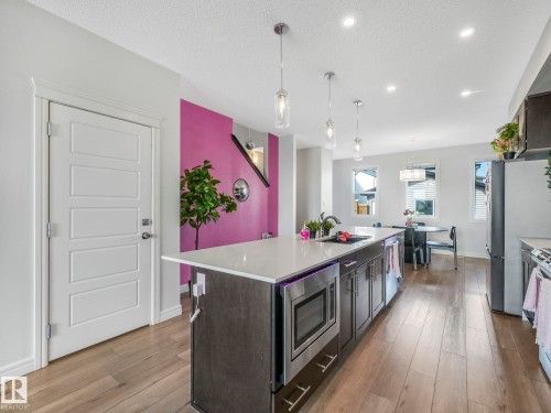 The kitchen features an island with a light-colored countertop and dark cabinetry, equipped with a microwave - 2636 192 Street, Edmonton, AB - Indoor Photo Showing Kitchen With Upgraded Kitchen